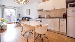 A modern kitchen with white cabinets, a dining area with a table and chairs, and a balcony with a view.