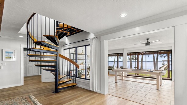 Un intérieur moderne avec un escalier en bois, un coin repas offrant une vue agréable et une grande fenêtre.
