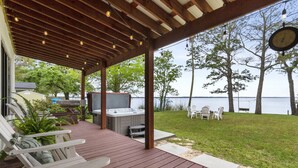 Une terrasse extérieure couverte, dotée d’un jacuzzi, de sièges et offrant une vue sur l’eau.