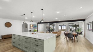Une cuisine spacieuse dotée d’un îlot central, de luminaires suspendus et d’un coin repas offrant une vue agréable.