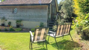 A wooden cabin with a tiled roof, a small porch, and two chairs in the foreground. - Detox Dunchideock (Exeter)