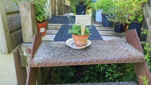 A rustic outdoor seating area with a metal table and benches, surrounded by potted plants and a wooden fence. - Detox Dunchideock (Exeter)