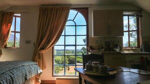 A room with a bed, a table with kitchen items, and a large window with curtains. - Detox Dunchideock (Exeter)