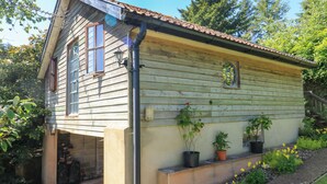 A wooden house with a sloped roof, a small porch, and potted plants on the front. - Detox Dunchideock (Exeter)