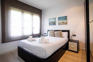A modern bedroom with a large bed, bedside tables, and artwork on the walls.