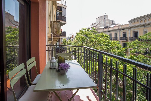 A balcony with a table, chairs, and a potted plant.