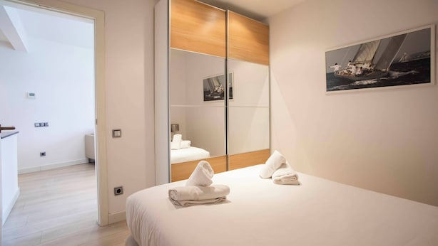 Een hotelkamer met een bed, een grote spiegel en een schilderij van een zeilboot.