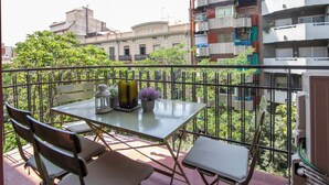 Een balkon met een tafel, stoelen en een bloempot.