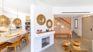 Eine moderne Küche mit weißen Schränken, ein Essbereich mit Holzkästen, ein Kamin und dekorative Spiegel.