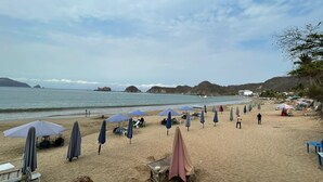 A beach with umbrellas, chairs, and tables set up for sunbathing.