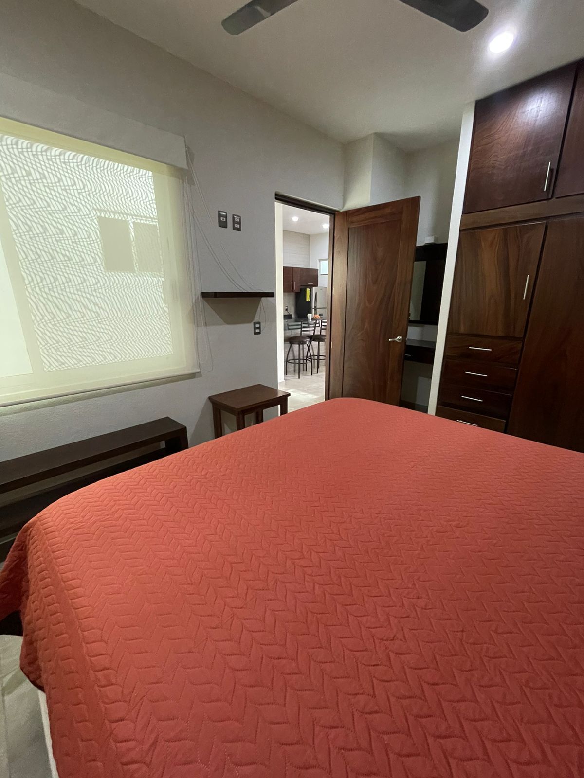 Quarto com cama grande, guarda-roupa de madeira e janela com vista para o exterior.