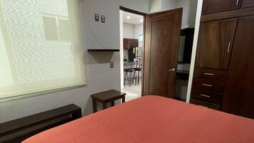 Quarto com cama grande, guarda-roupa de madeira e janela com vista para o exterior.