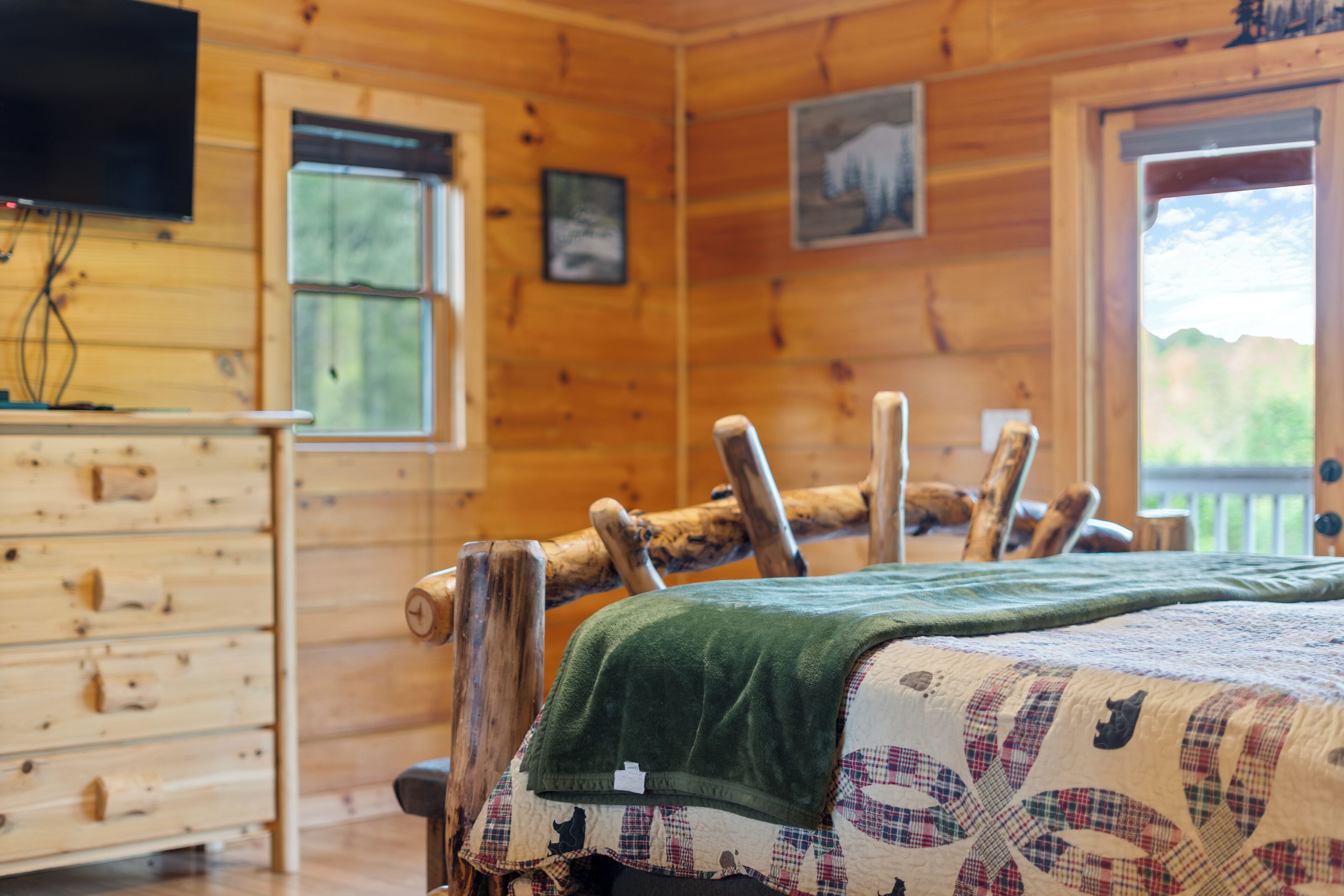 Habitación de cabaña de madera con cama, cómoda y ventanas.