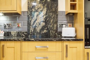 A kitchen with a marble backsplash, wooden cabinets, and a toaster.