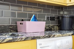 A kitchen with a pink storage bin, a black pot, and a white dishwasher.