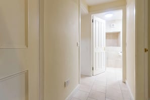 A hallway with white walls and tiled flooring leading to a bathroom with a shower and a toilet. - Central 3BD Home Short walk to Edinburgh Old Town (Edinburgh)