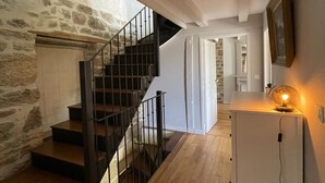 Un escalier menant à un mur de pierre, un plancher en bois et une porte blanche.