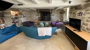 Un salon chaleureux avec un mur en pierre, une cheminée, un téléviseur et un canapé.
