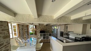 Une cuisine moderne avec des meubles blancs, un îlot central et un coin repas comprenant une table et des chaises.
