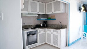 A compact kitchen with white cabinets, a microwave, a stove, and a sink.