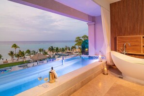 A balcony with a view of the ocean, a pool, and a bathtub.