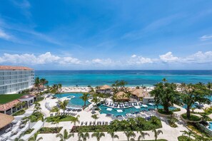 A resort with a large pool, palm trees, and a view of the ocean.