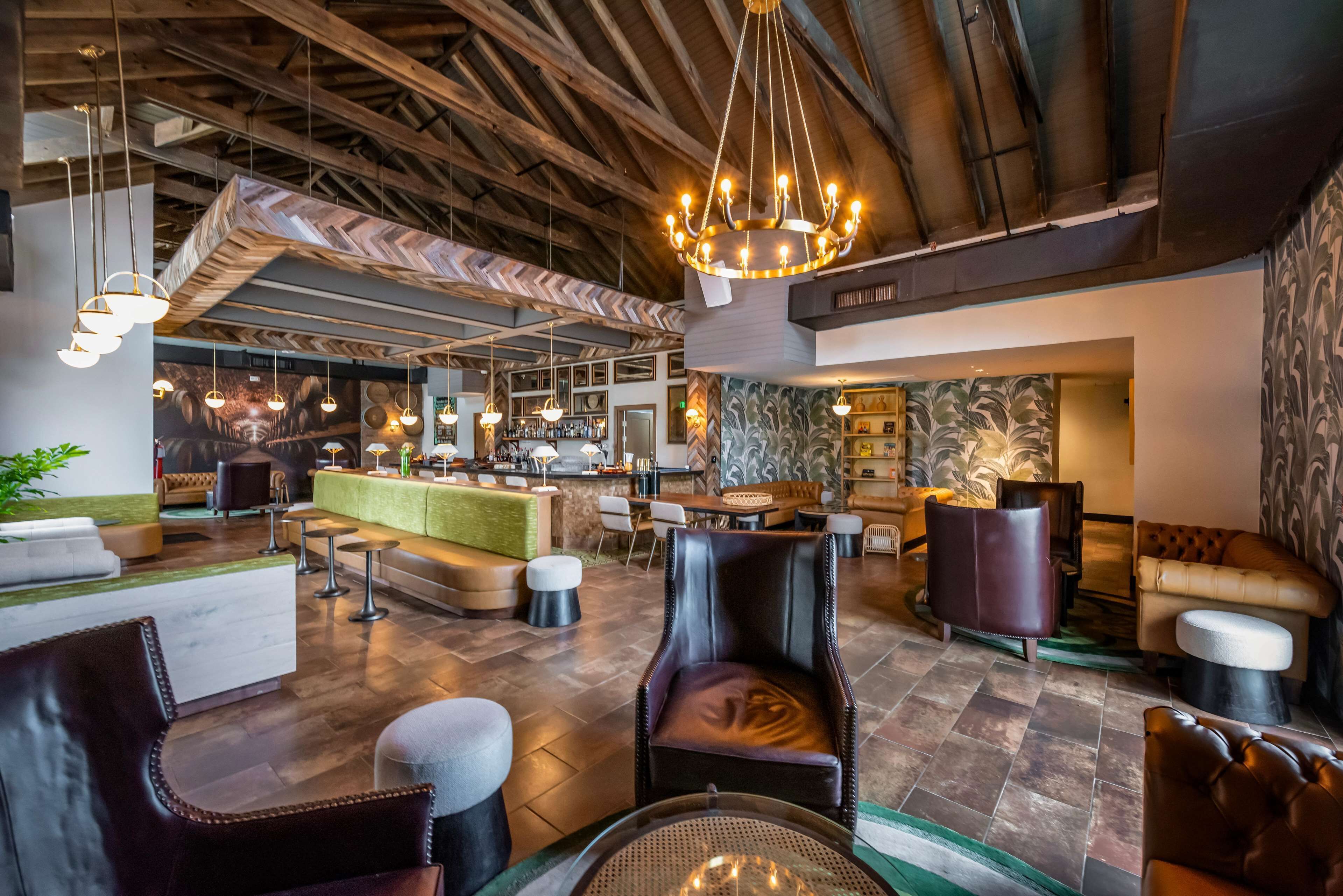 A spacious lobby with a high ceiling, leather seating, a bar area, and a patterned wall.