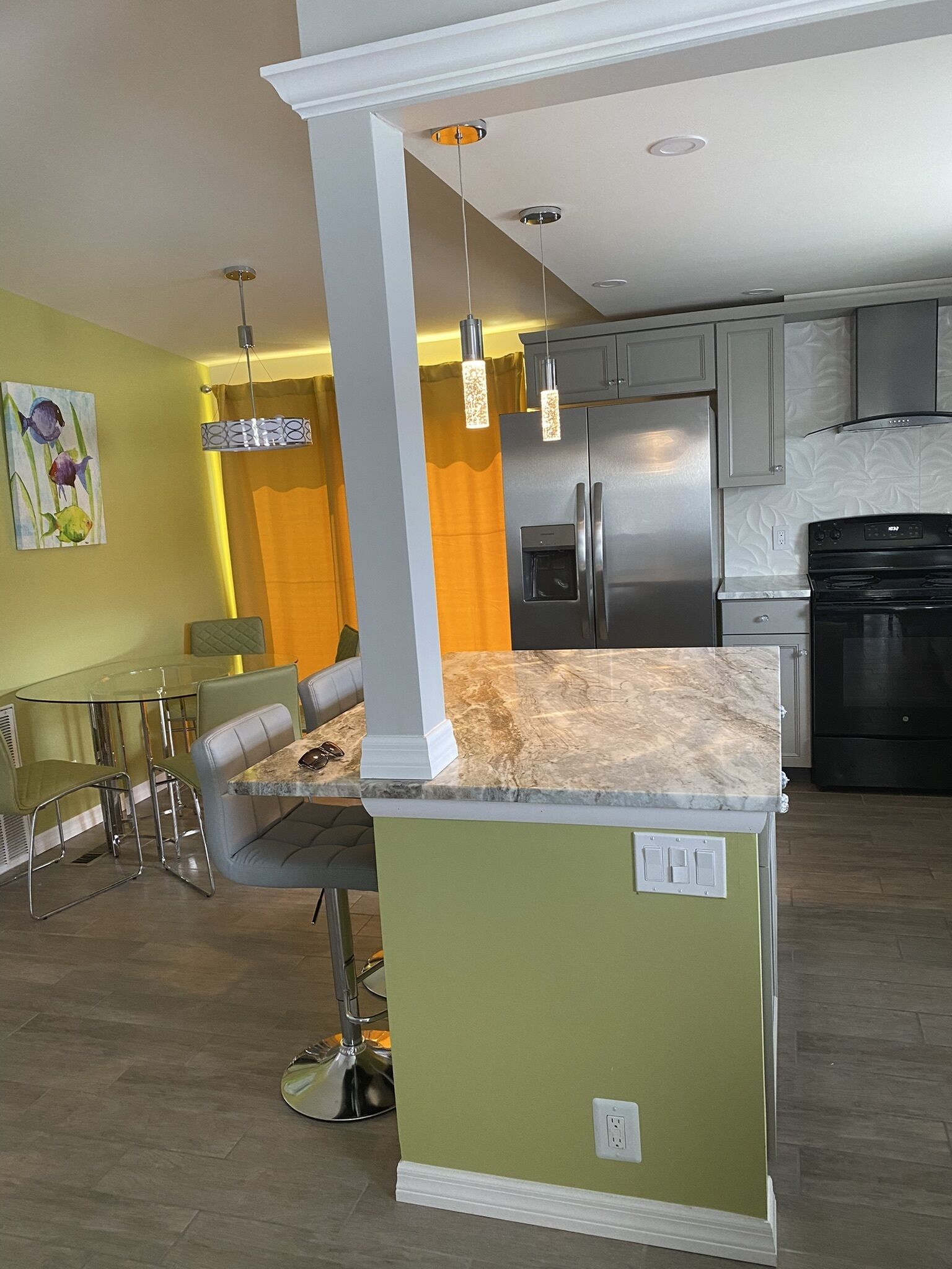 A modern kitchen with a central island, stainless steel appliances, and pendant lighting.
