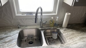 A kitchen with a double sink, a window above the sink, and a marble countertop. - Beautiful 55+ Senior Gated Oasis: Pool, Pickleball & Small Pets Welcome! (punta gorda)