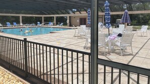 A covered outdoor swimming pool with lounge chairs and umbrellas. - Beautiful 55+ Senior Gated Oasis: Pool, Pickleball & Small Pets Welcome! (punta gorda)
