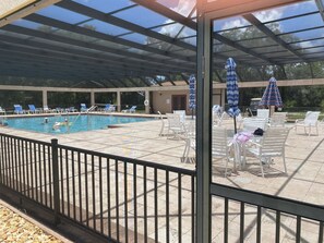 A covered outdoor swimming pool with lounge chairs and umbrellas. - Beautiful 55+ Senior Gated Oasis: Pool, Pickleball & Small Pets Welcome! (punta gorda)