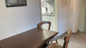 A dining area with a wooden table and two chairs, a framed picture on the wall, and a view of the outside through a door. - Small vacation apartment in Bad Lauchstädt (Goethestadt Bad Lauchstädt)