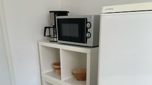 A kitchenette with a microwave, a coffee maker, and a white refrigerator. - Small vacation apartment in Bad Lauchstädt (Goethestadt Bad Lauchstädt)
