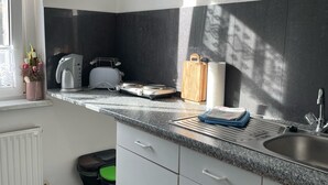 A kitchen with a granite countertop, white cabinets, a built-in oven, and a window with a view of the outside.