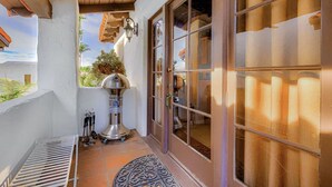 A patio with a grill, a metal bench, and a door with glass panels. - Experience San Clemente's Historic Charm in Our Beautifully Furnished Studio (San Clemente)