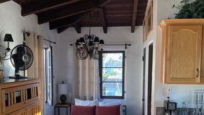 A bedroom with a bed, wooden furniture, a window with curtains, a chandelier, and a view of the outside. - Experience San Clemente's Historic Charm in Our Beautifully Furnished Studio (San Clemente)