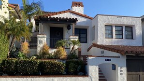 A two-story house with a white exterior, a brown roof, and a small front porch. - Experience San Clemente's Historic Charm in Our Beautifully Furnished Studio (San Clemente)