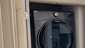 A compact, modern laundry room with two stacked front-loading washing machines.