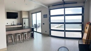 A modern kitchen with a bar area, large windows, and a view of the sea.