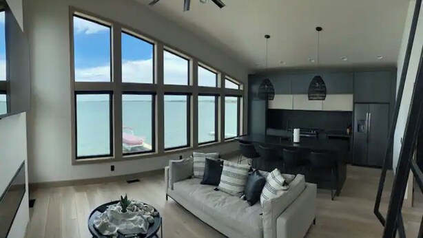 A spacious living area with a large window, a sofa, a coffee table, and a kitchen area with modern appliances.