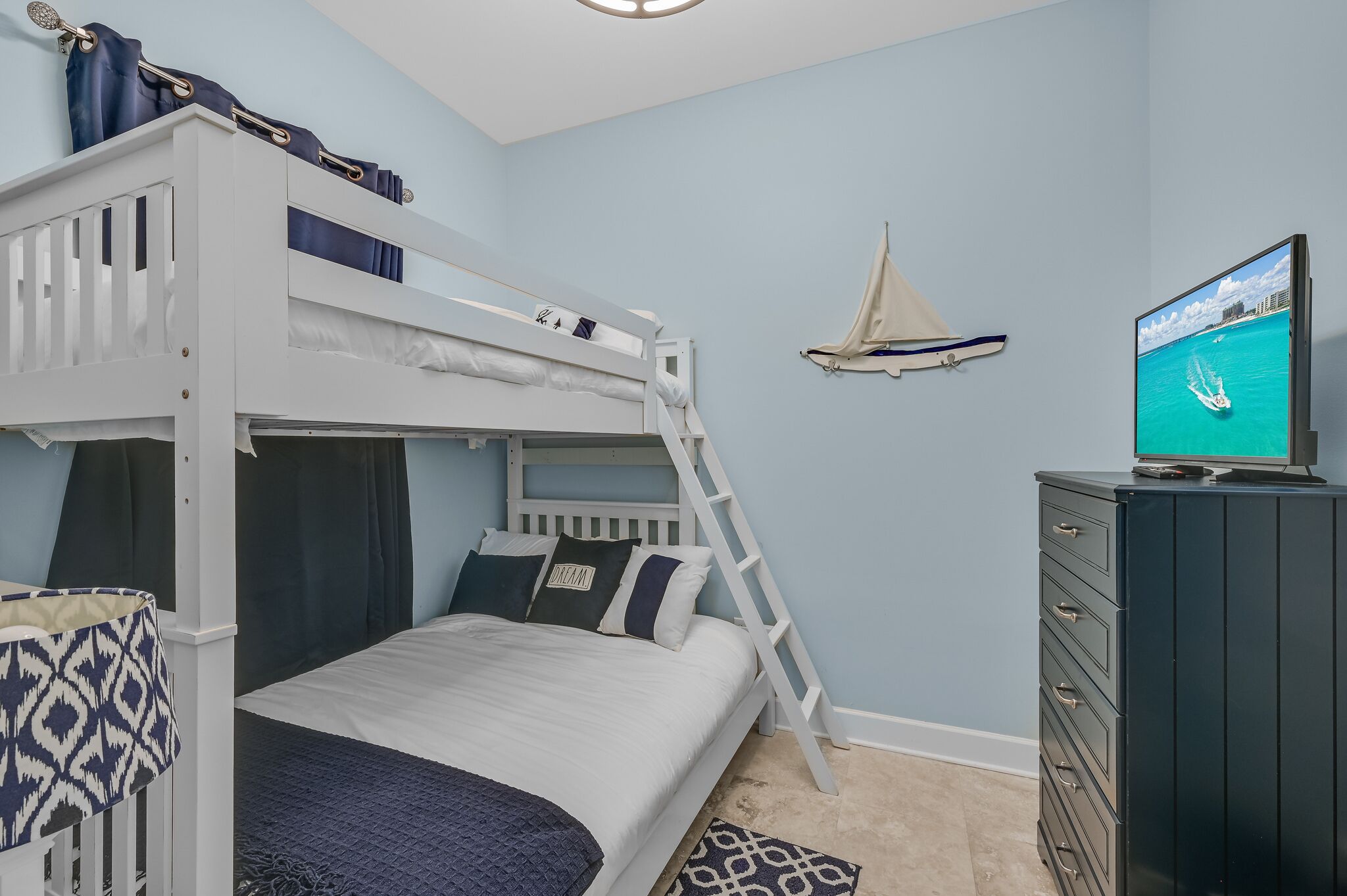 Habitación con literas, televisión, decoración de velero y cómoda.