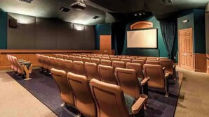Une salle de cinéma avec des rangées de sièges, un grand écran et une cabine de projection.