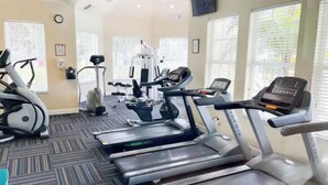 Une salle de sport équipée de tapis de course, de vélos elliptiques et de matériel de musculation.