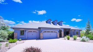 Une maison à deux étages avec un garage, une allée couverte et un jardin aménagé à l’avant.