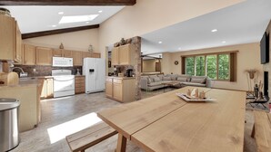 A spacious kitchen with wooden cabinets, a large island, and a dining area with a long table.