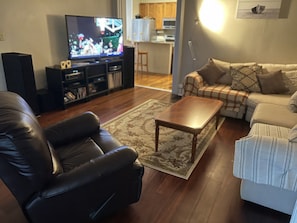 Relax in this stylish living room with a flat-screen TV, leather armchair, and comfortable sofa.
