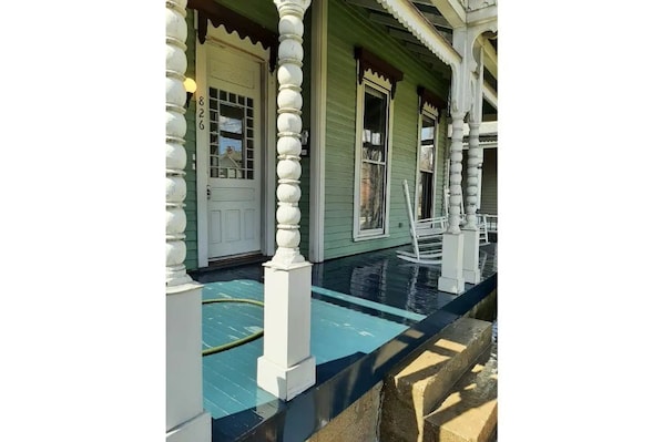 Traditional house with a charming porch featuring a white balustrade and a green exterior.