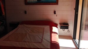 A bedroom with a bed, a painting on the wall, a bedside table, and a window. - House with swimming pool in the pines 500M from the sea (MARTIGUES)
