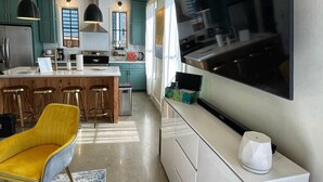 Eine moderne Küche mit großem Fernseher, Edelstahlgeräten und Türkis-Schränken.