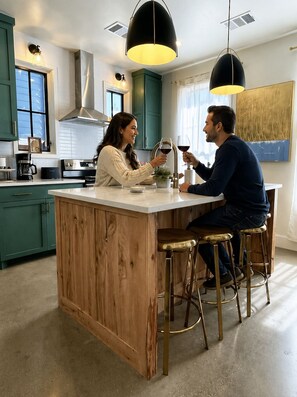 Une cuisine moderne dotée d’un îlot central, de tabourets de bar et de luminaires suspendus.